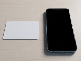 Blanko-Plastikkarte und Smartphone mit schwarzem Display auf hellem Holztisch