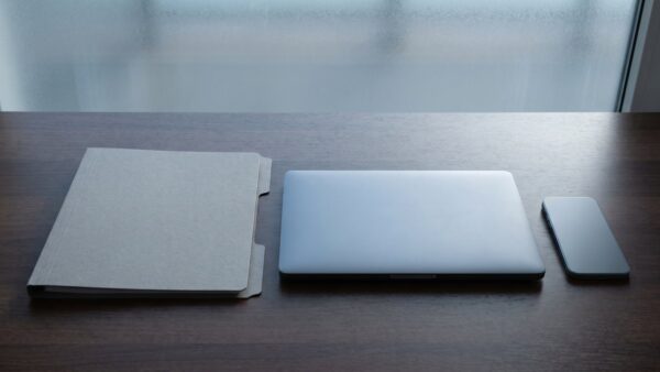 disney plus airplay bild 1 Unbeschrifteter Aktenordner neben einem zugeklappten Laptop und einem Smartphone auf einem Holztisch