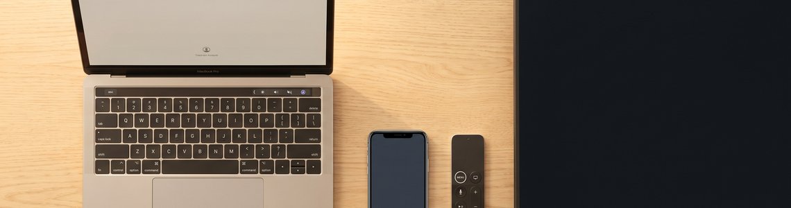 Schreibtisch mit Laptop, Smartphone, Fernbedienung und Fernseher als Symbolbild für die Anmeldung bei einem Streamingdienst