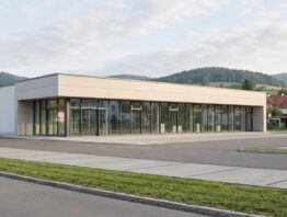 Modernes flaches Gewerbegebäude mit Glasfassade vor bewaldeten Hügeln