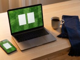 Notebook und Smartphone mit abstrakter Rasenfläche auf einem Schreibtisch neben einem Stadionschal