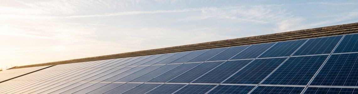 Reihe dunkelblauer Solarmodule auf einem Ziegeldach unter klarem Himmel