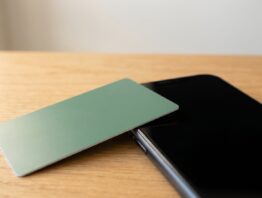 Unbedruckte grüne Kundenkarte neben Smartphone mit schwarzem Bildschirm