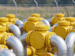 Gelbe Absperrventile und silberne Rohrbögen einer Gasspeicherstation bei Tageslicht