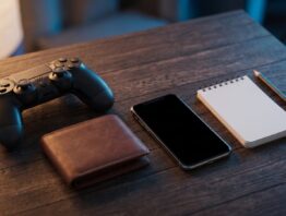 Gamecontroller, Portemonnaie und Smartphone auf einem dunklen Holztisch als Symbol für die Kosten von Cloud-Gaming