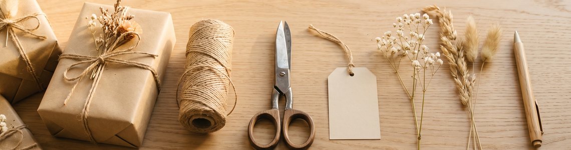 In Kraftpapier verpackte Geschenke mit Bastschnur und leeren Anhängern
