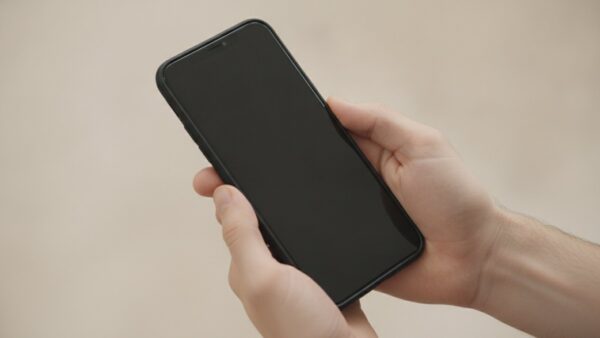 ghost pairing bild 3 Zwei Hände halten ein Smartphone mit schwarzem Display vor hellem Hintergrund
