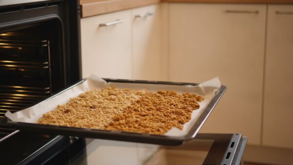 Granola auf einem Backblech wird bei niedriger Temperatur im Ofen goldbraun geröstet