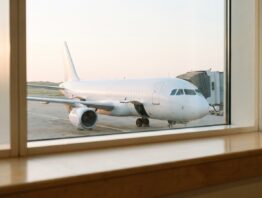 Weißes Flugzeug am Gate hinter einem Flughafenfenster
