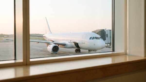 guenstig fliegen bild 1 Weißes Flugzeug am Gate hinter einem Flughafenfenster