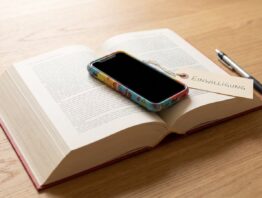 Gesetzbuch mit Smartphone in Kinderhuelle und Schild Einwilligung auf dem Tisch