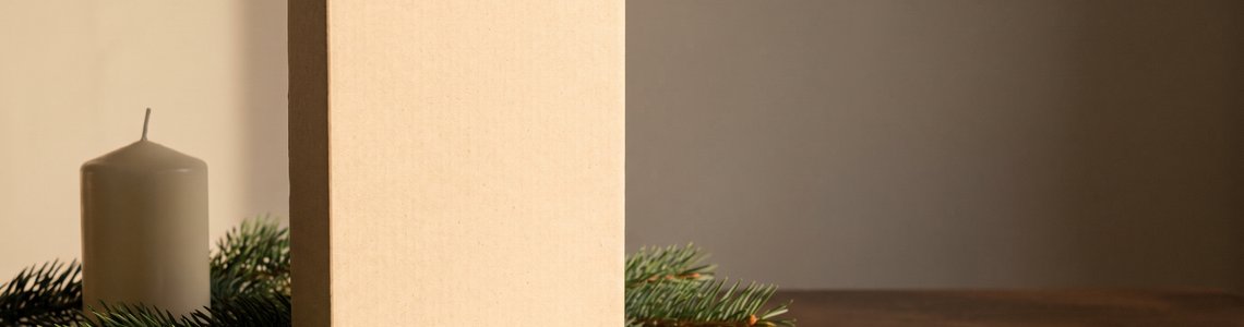 Unbedruckter Kalenderkarton aus Naturkarton mit Tannenzweigen auf dunklem Holztisch