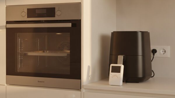 heissluftfritteuse test bild 3 Backofen und Heißluftfritteuse in einer Küche, davor ein Energiemessgerät in der Steckdose