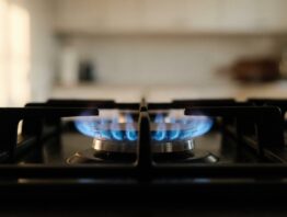 Blaue Gasflamme auf einem schwarzen Kochfeld als Sinnbild für den Erdgasverbrauch