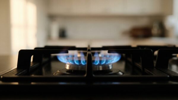 Blaue Gasflamme auf einem schwarzen Kochfeld als Sinnbild für den Erdgasverbrauch
