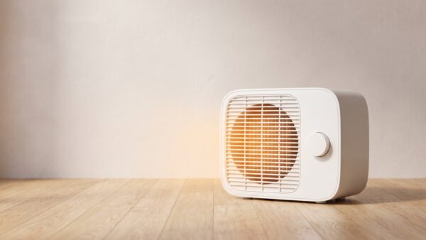 heizluefter bild 1 Weißer Keramik-Heizlüfter mit warm leuchtendem Lüftungsgitter auf einem Holzboden