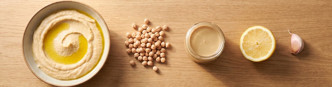 Zutaten fuer Hummus selber machen auf Holztisch