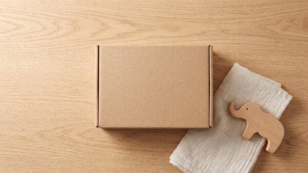 Schlichte Pappbox mit Babyartikeln auf einem hellen Holztisch