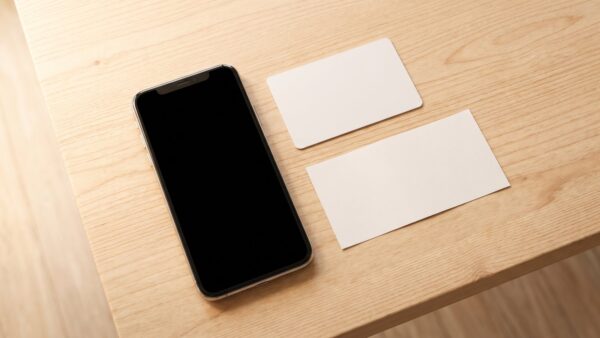 Smartphone mit dunklem Bildschirm neben blanko Karte und leerem Zettel