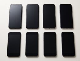 Zwei Reihen Smartphones verschiedener Baujahre mit ausgeschalteten Displays im Vergleich