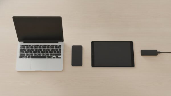 joyn login bild 2 Laptop, Tablet, Smartphone und Streaming-Stick nebeneinander auf einem Holztisch, alle Bildschirme dunkel