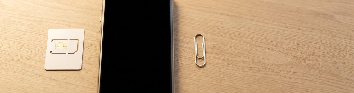Unbedruckte SIM-Karte und ausgeschaltetes Smartphone auf hellem Schreibtisch