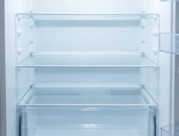 Leere Glasablagen und Gemüseschublade im Kühlschrank