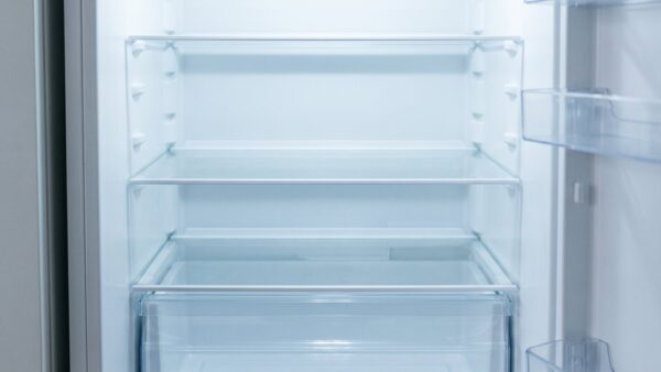 Leere Glasablagen und Gemüseschublade im Kühlschrank