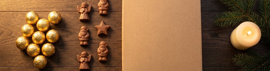 Schokoladenkugeln und Figuren neben einem Adventskalenderkarton