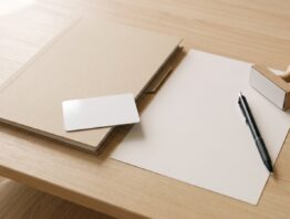 Unbedruckte weiße Plastikkarte auf einer leeren Mappe neben Kugelschreiber und Stempel