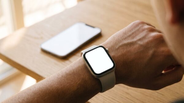 Smartwatch am Handgelenk mit dem Smartphone im Hintergrund