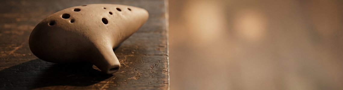 Schlichte Okarina aus mattem Ton auf einem dunklen Holztisch mit viel freier Fläche