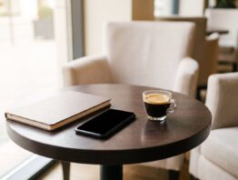 Zugeklapptes Notebook und ausgeschaltetes Smartphone auf einem Cafétisch in einer Hotellobby