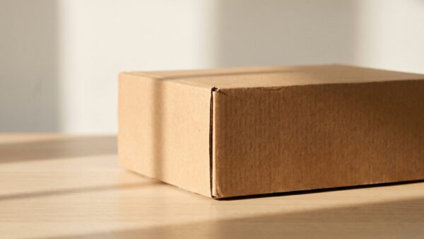 paketweiterleitung bild 1 Einzelner unbedruckter brauner Karton auf heller Holzfläche