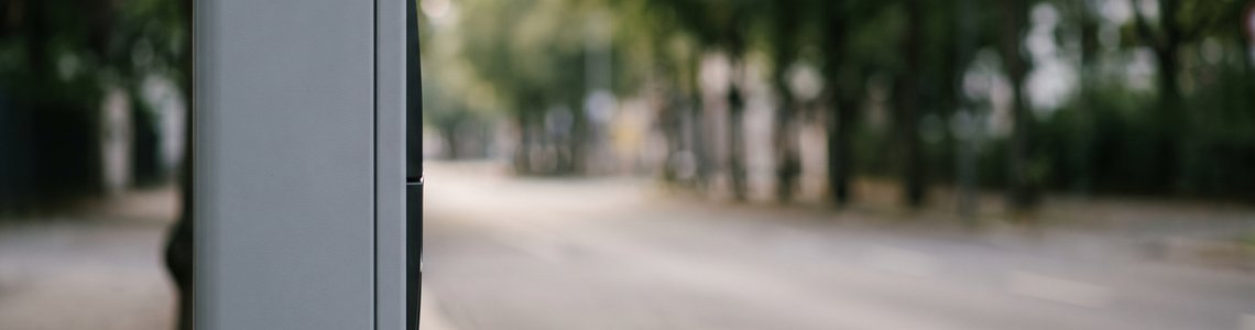 Leere innerstädtische Parkbucht mit unbeschriftetem Parkscheinautomaten im Morgenlicht