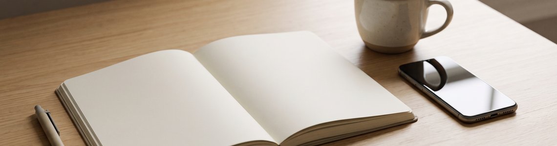 Aufgeschlagenes leeres Notizbuch mit Stift und Kaffeetasse auf einem hellen Schreibtisch