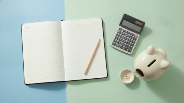 paypal plus bild 3 Leeres Notizbuch, Bleistift, Taschenrechner und Sparschwein auf einem hellen Schreibtisch