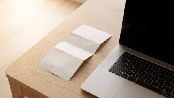 paysafecard guenstig bild 1 Kassenbon mit Guthabencode neben dem Laptop