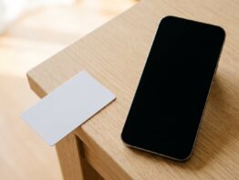 Smartphone mit schwarzem Bildschirm neben unbedruckter Plastikkarte