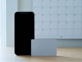 Smartphone mit schwarzem Bildschirm neben unbedruckter Karte vor leerem Kalender