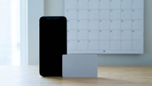 Smartphone mit schwarzem Bildschirm neben unbedruckter Karte vor leerem Kalender