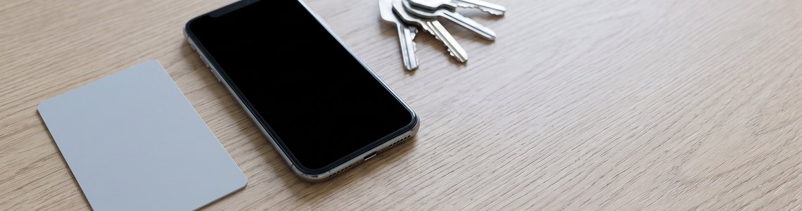 Unbedruckte Karte und Smartphone mit schwarzem Bildschirm auf heller Holzfläche