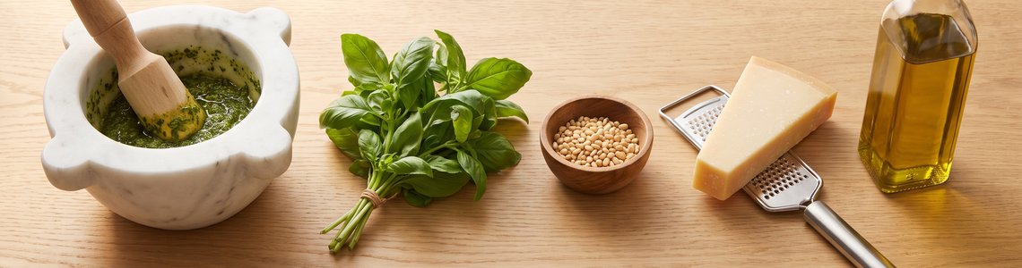 Zutaten fuer Pesto selber machen auf Holztisch mit Marmormoerser