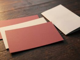 Vier unbedruckte Papiergutscheine überlappend auf dunklem Holztisch