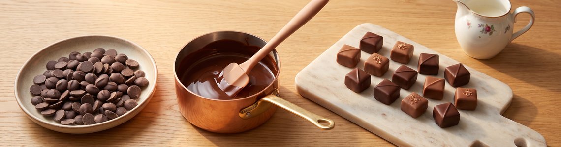 Pralinen selber machen - Kuvertuere, Ganache und fertige Pralinen auf Holztisch