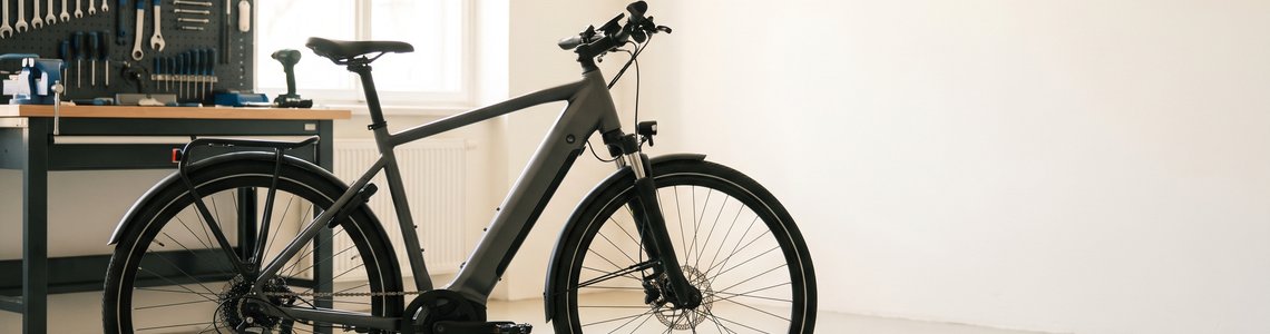 Dunkelgraues E-Bike ohne Markenzeichen seitlich in einer hellen Werkstatt