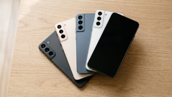 Vier moderne Smartphones in aufsteigender Größe fächerförmig auf einem hellen Eichentisch