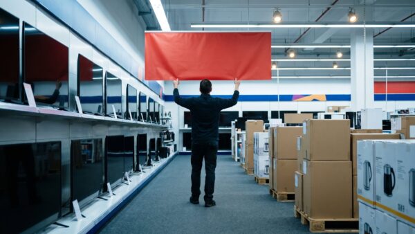 saturn wird mediamarkt bild 1 Mitarbeiter hängt in einem Elektronikmarkt vor der Öffnung ein neues Banner auf