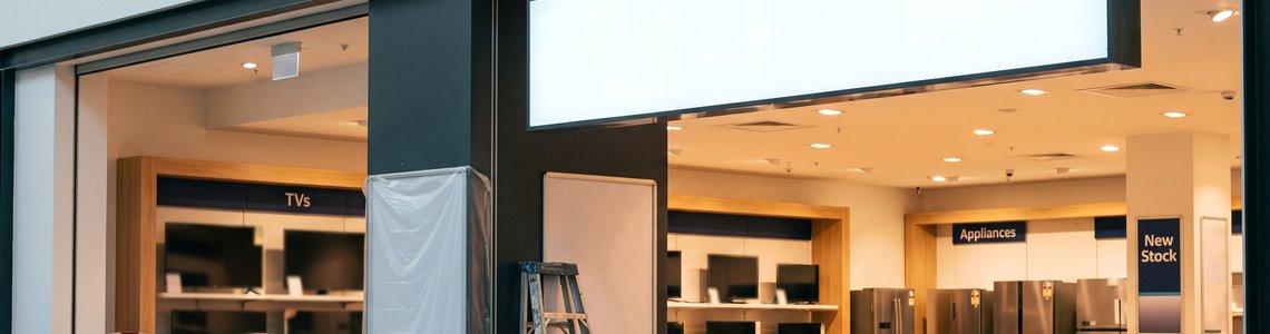 Eingang eines Elektronikfachmarkts im Umbau mit leerem Leuchtkasten über der Tür