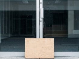 Geschlossene Glastür eines Ladens mit leerem Verkaufsraum dahinter